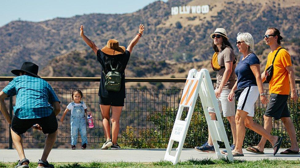 Tourists posing in front of the hollywood sign, which is blurred and in the background