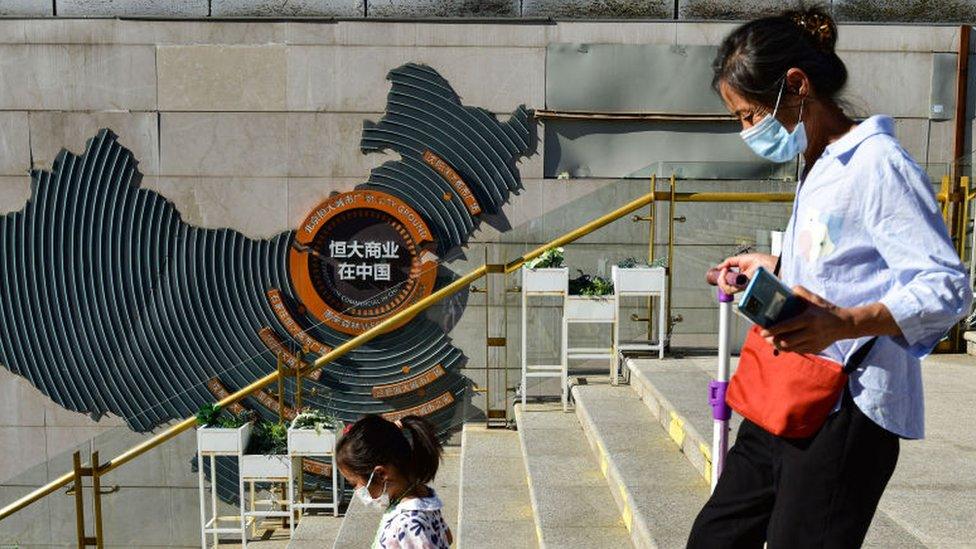 A woman with a child seen passing in front of Evergrande group's blueprint for development in China at Evergrande city square, Chaoyang District.