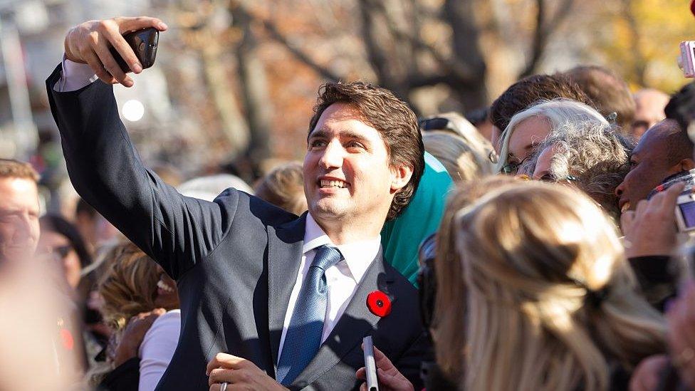 Justin Trudeau taking selfies with fans.