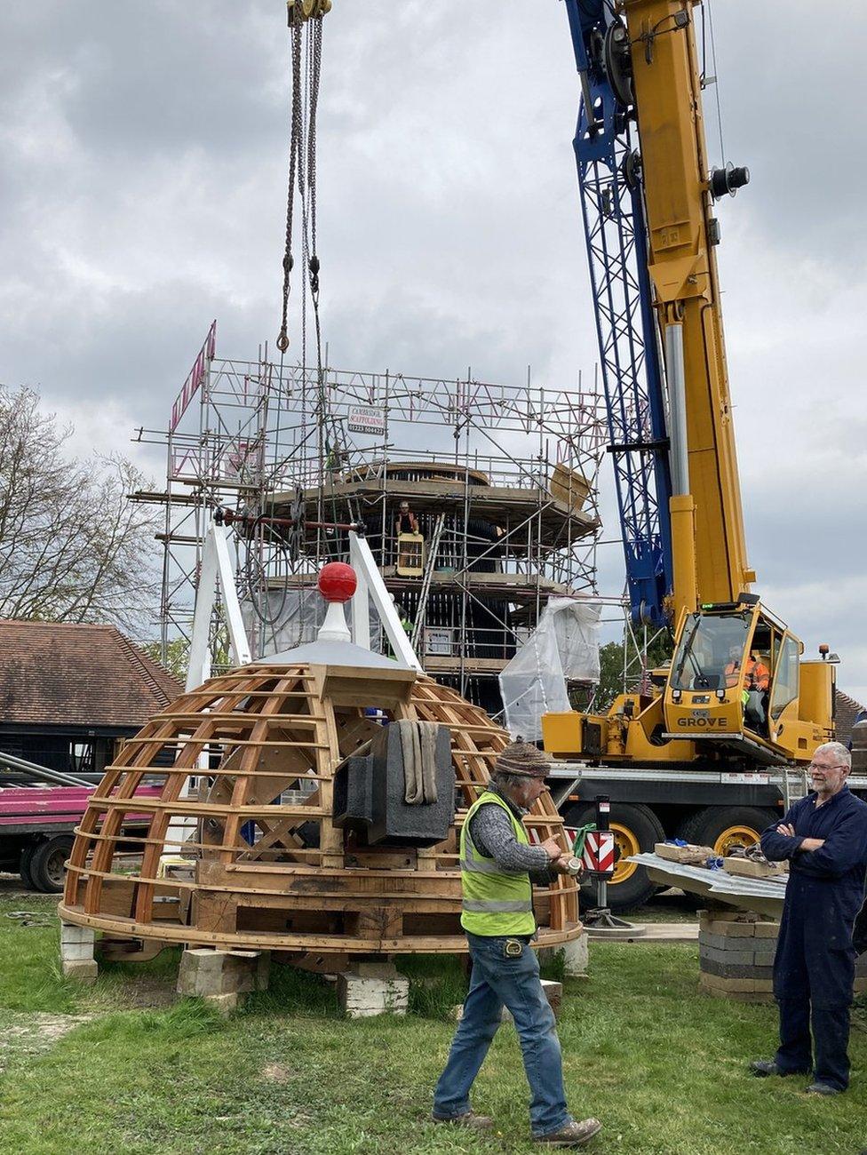 The windmill's cap attached to a crane on the ground.