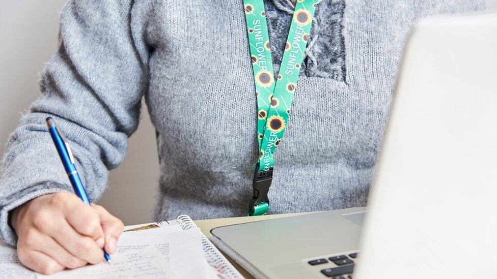 An adult wearing a Sunflower lanyard