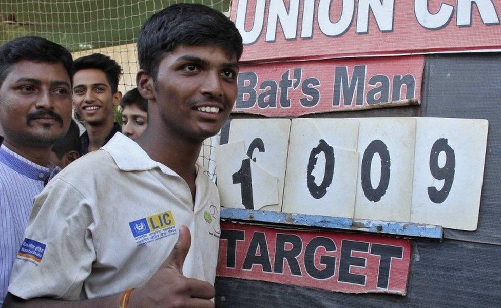 Schoolboy Pranav Dhanawade, 15, gestures as he poses next to the scoreboard during an inter-school cricket tournament in Mumbai, India, January 5, 2016.