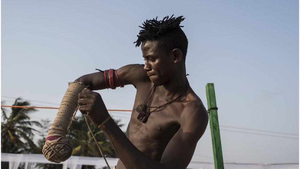 Dambe fighter wraps up his arm with rope known as "Kara"