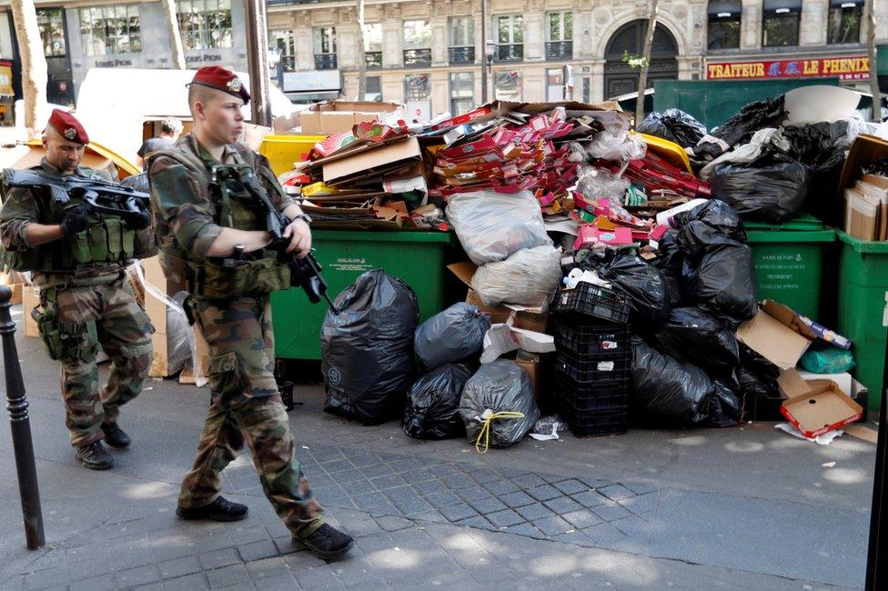 French soldiers pass uncollected rubbish in Paris, 9 June