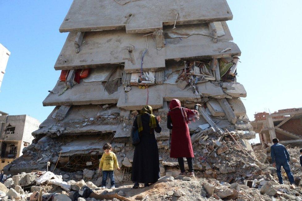 People stand among the rubble of damaged buildings following heavy fighting between government troops and Kurdish fighters in the Kurdish town of Cizre on 2 March 2016