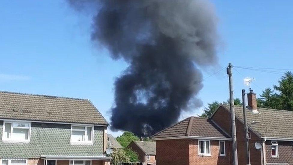 Black smoke coming from behind houses