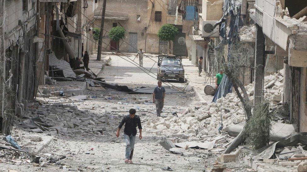 People walk past damaged buildings after an air strike in the rebel-held Baedeen district of Aleppo, Syria (3 May 2016)