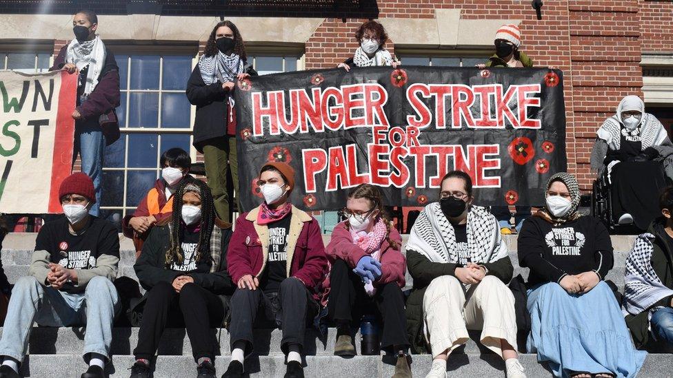 Students on Brown's campus holding a sign that says 'Hunger Strike for Palestine'