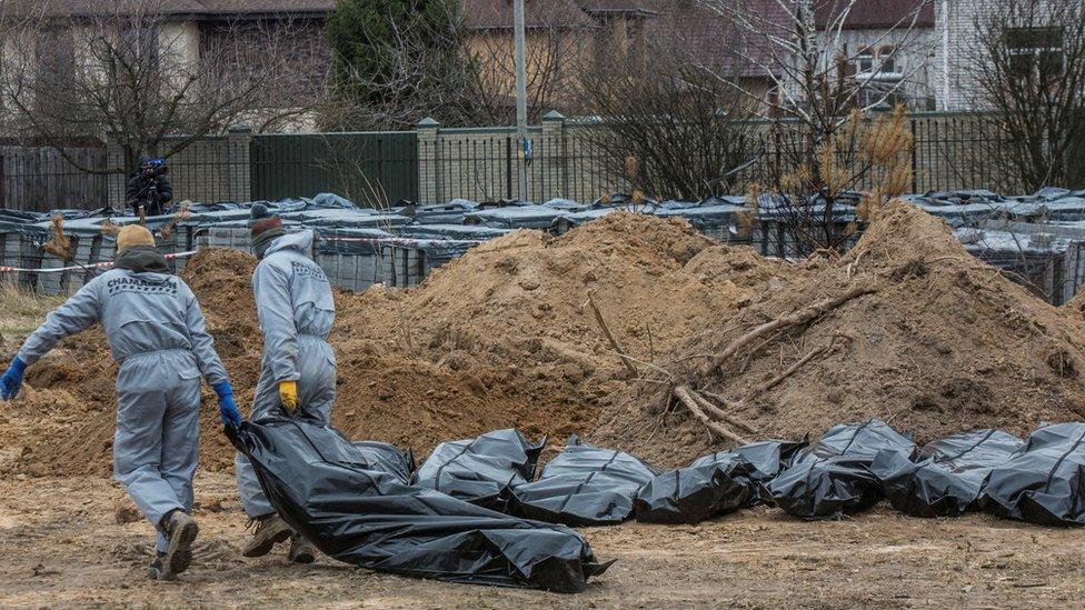 Forensic technicians carry pull the body of a civilian who Ukrainian officials say was killed during Russiaâ€™s invasion, then buried and exhumed from a mass grave in the town of Bucha, outside Kyiv