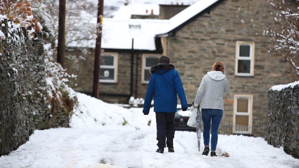 People walk on snowy conditions in Blaenau Ffestiniog in Wales