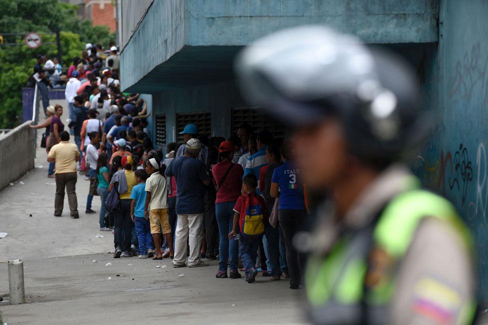 Police monitor a supermarket queue in Petare, Caracas on 1 June 2016