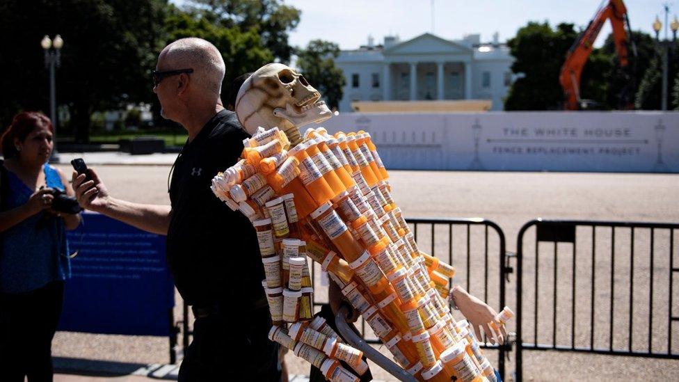 Frank Huntley, who struggled with addiction, walks with Pill Man, a skeleton made from his oxycontin and methadone prescription bottles