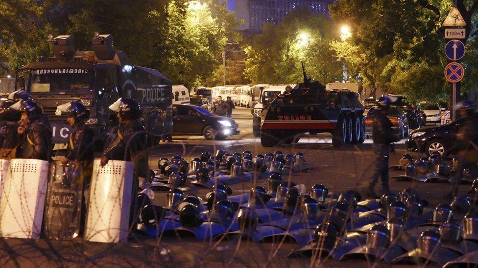 Police stand guard against the protesters