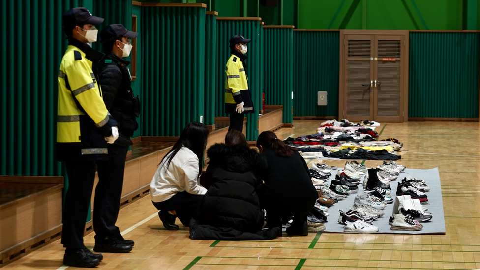 A group of survivors or relatives of victims pick out items that belonged to them or their loved ones