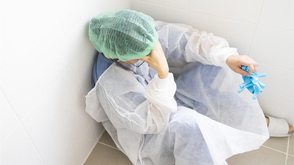 A health worker with their head in their hands