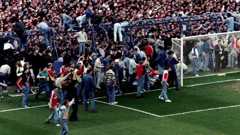 Fans climbing over pitch barrier