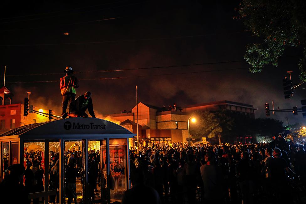 Protesters gather around after setting fire to the entrance of a police station