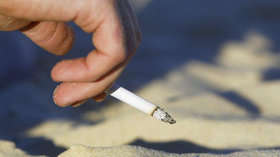 A smoker enjoys a cigarette on a beach