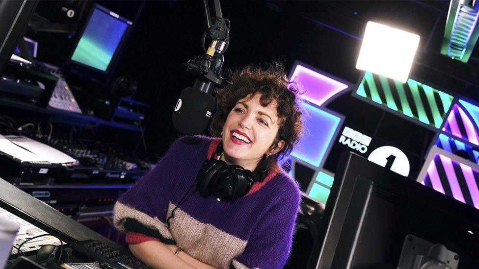 Annie Mac in the studio smiling with her headphones around her neck