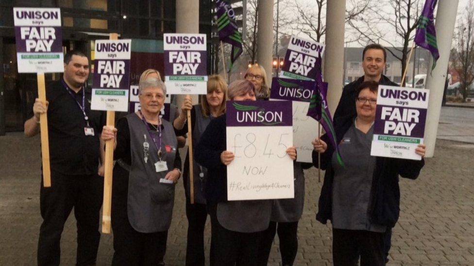 Cleaners hold placards outside Newport City Campus on Tuesday