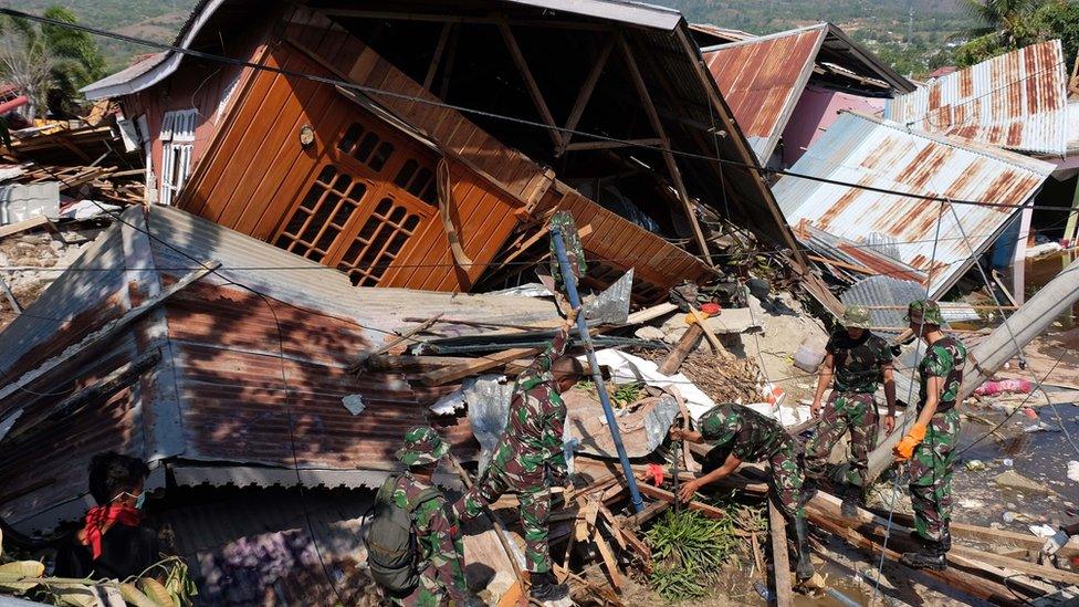 Rescue personnel search for survivors at a collapsed home in Balaroa, West Palu