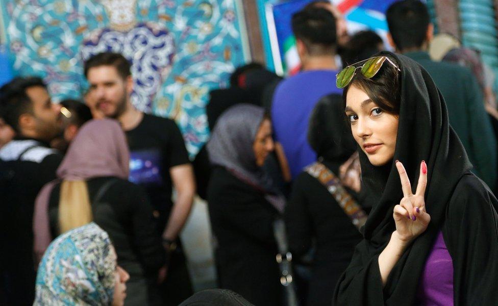 An Iranian woman (R) flashes the victory sign as she waits with others to cast her ballot in the Iranian presidential elections at a polling station in Tehran, Iran, 19 May 2017