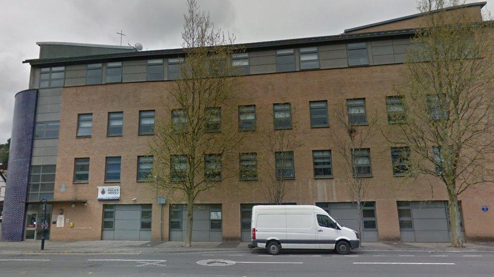 An image of Swansea Central Police Station. It is a new looking building built from sand coloured bricks and has grey windows and has five floors.