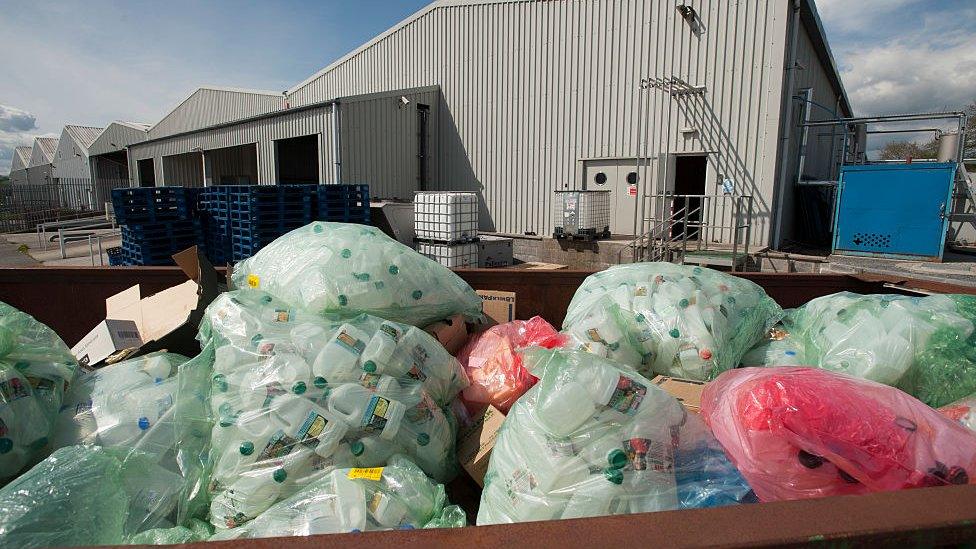 Empty plastic milk containers bagged in a skip at a recycling centre