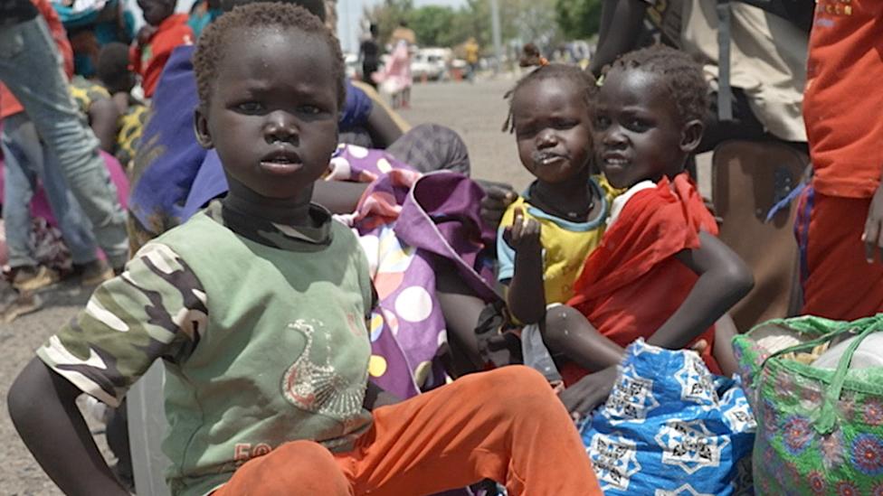 Children waiting on the tarmac of an airport