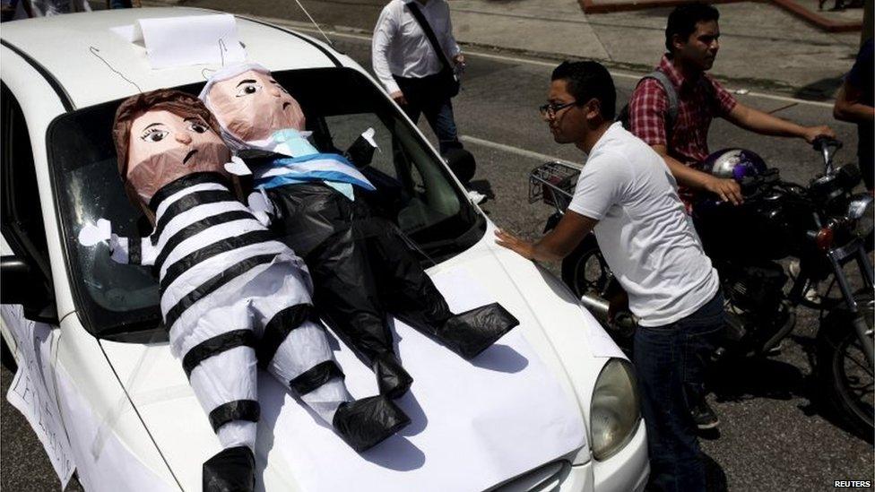 A cab driver looks at pinatas depicting former Vice President Roxana Baldetti (left) and Guatemalan President Otto Perez Molina during a demonstration demanding the resignation of Mr Perez Molina in Guatemala City on 27 August, 2015