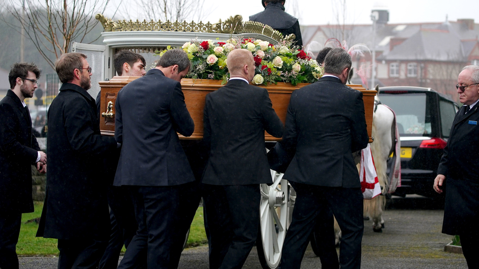 The bearer party carry the coffin of Elle Edwards into her funeral