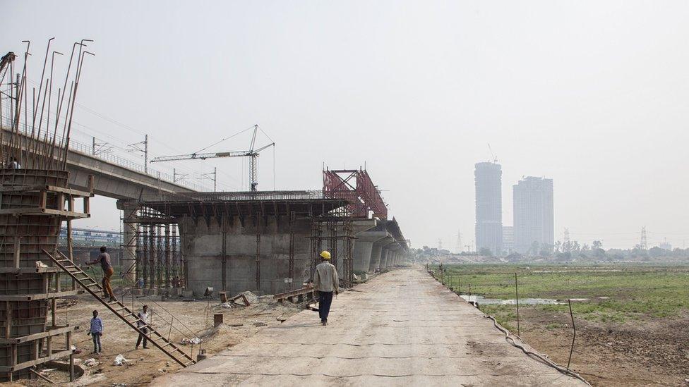 An Indian worker walks on a temporary bridge at a construction site along the Yamuna River in New Delhi on May 28, 2018