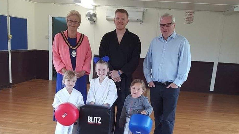 Gavin posing with three young children and two other adults in the martial arts centre