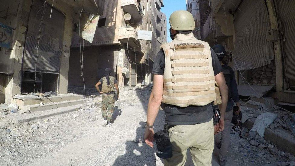 Figures walk through devastated street in Raqqa