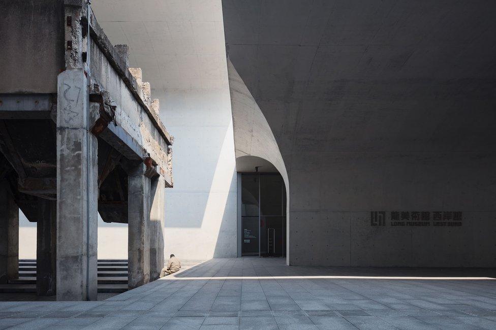 A man sitting on the ground surrounded by concrete architecture