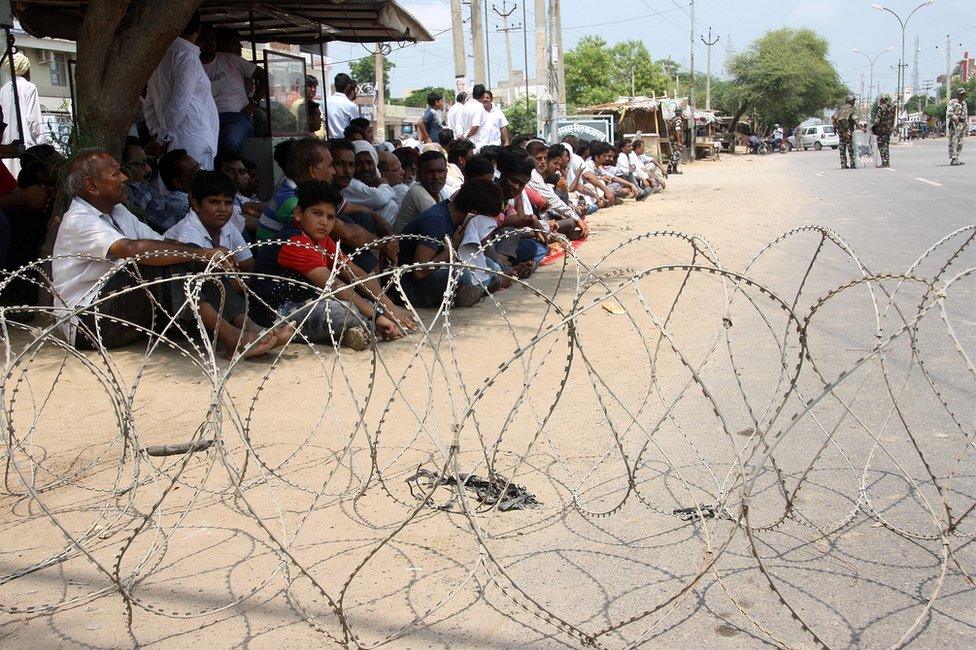 Mr Singh's supporters sit beyond barbed wire