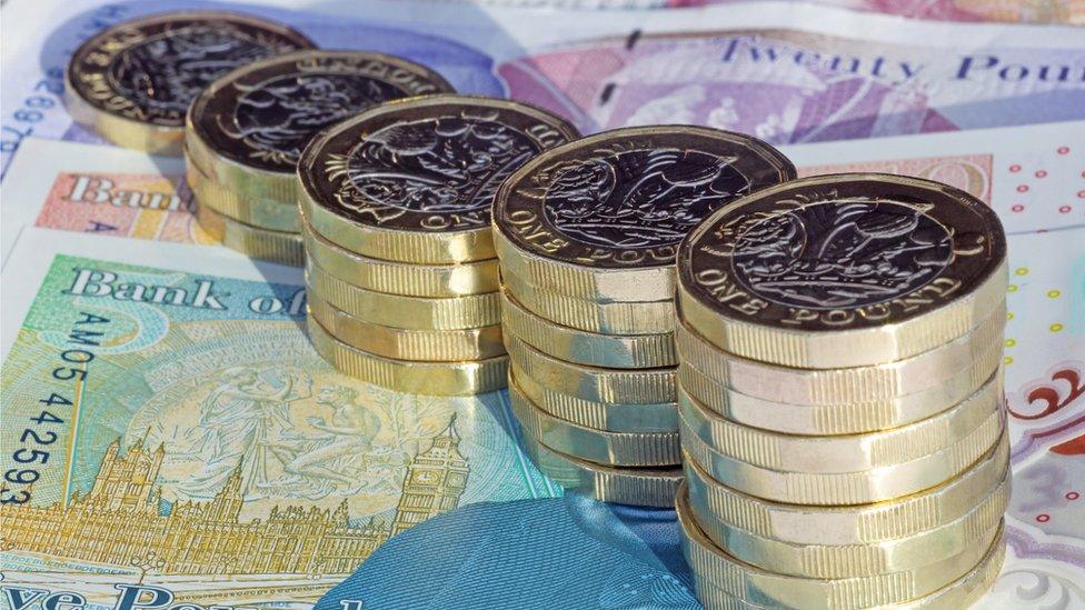 Stacks of one pound coins on British pound notes. - stock photo