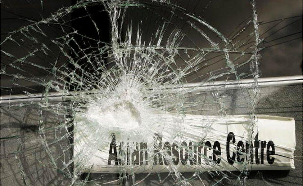 A sign saying Asian Resource Centre is seen behind smashed glass in Lozells on October 23, 2005 in Birmingham