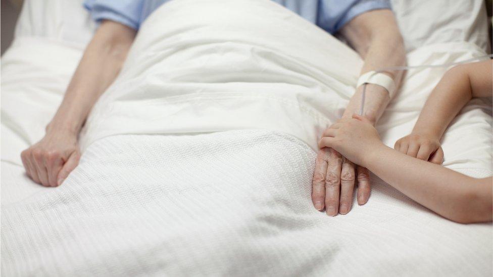 Child holds hands with hospital patient