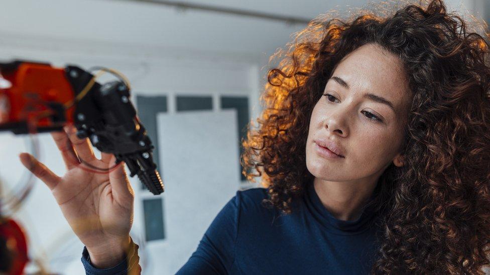 Woman in office looking at robotic arm