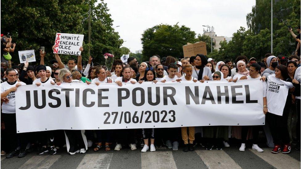 Protestors hold a banner reading "Justice for Nahel"