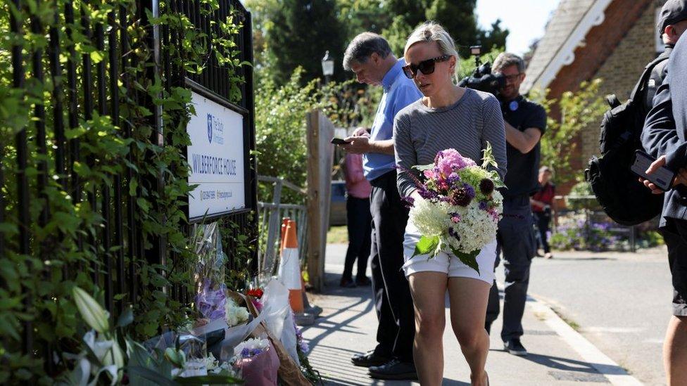 A woman lays flowers by railings at Wilberforce House at the school.