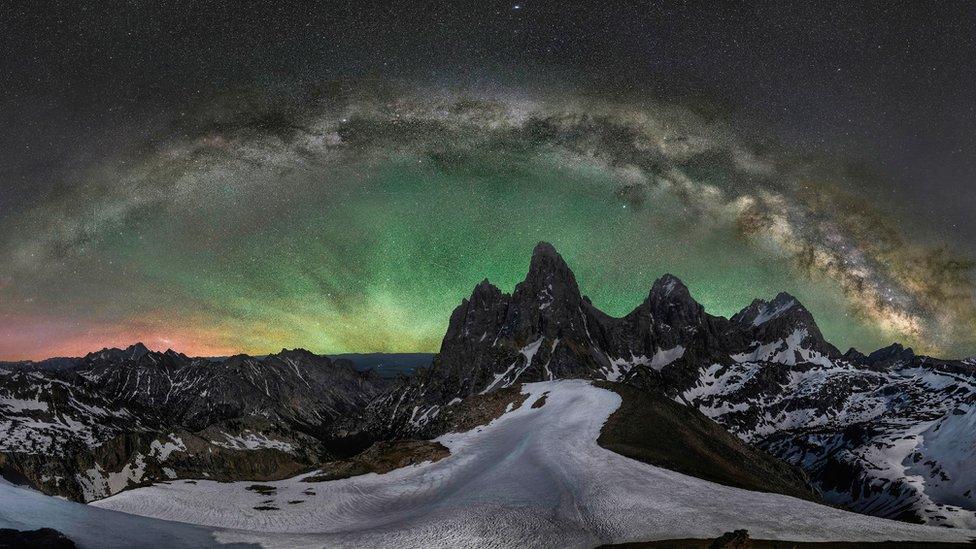 The Northern Lights highlight the Grand Teton Mountain in a halo of reds, yellows and greens.