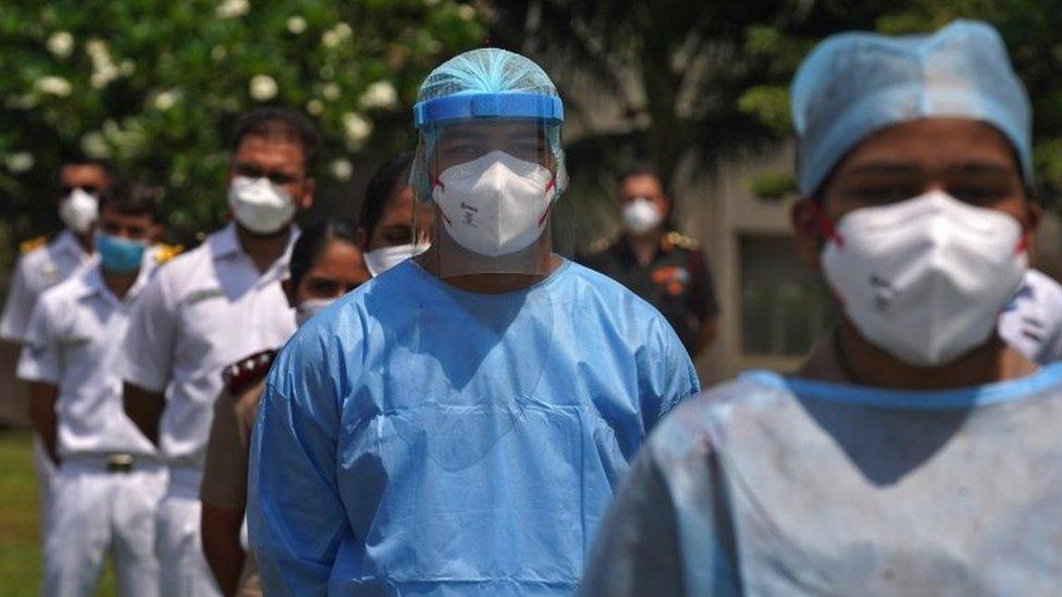 The staff of INHS Asvini hospital wearing protective gear stand before they were showered with flower petals by Indian Navy"s Chetak helicopter as part of an event to show gratitude towards the frontline warriors fighting the coronavirus disease (COVID-19) outbreak, in Mumbai