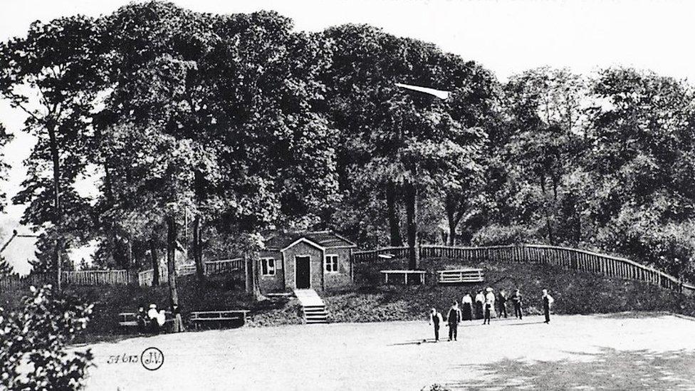 Black and white photo show green in the foreground with people playing