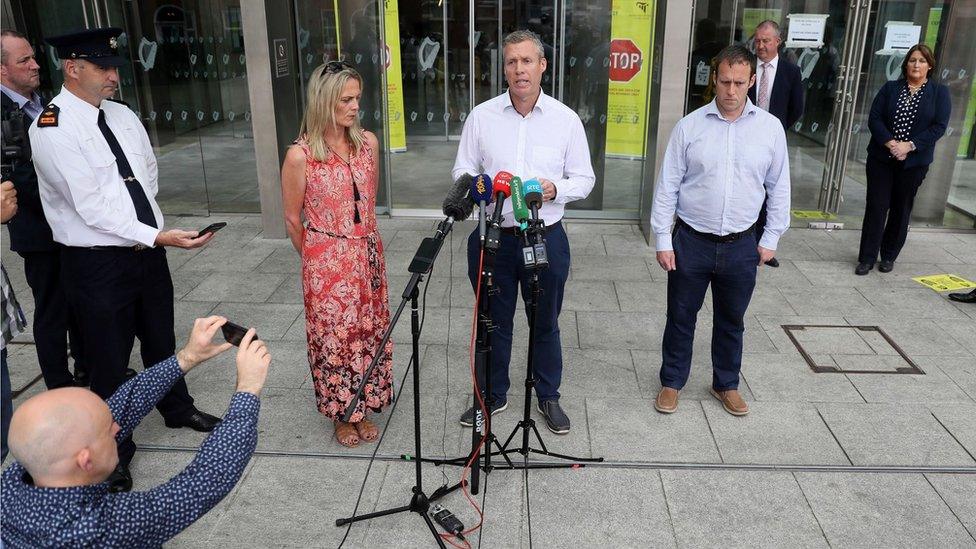 Garda Colm Donohoe (centre) read a family statement outside court