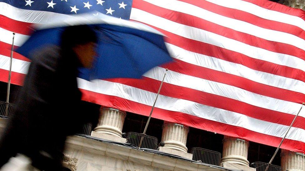 US flag and pedestrian on Wall Street