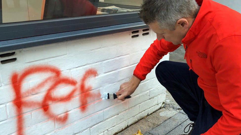 Luke Pollard painting over graffiti outside his office