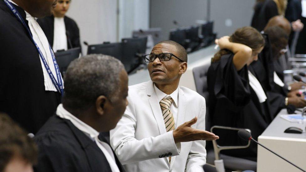 Narcisse Arido (C) talks with his lawyer in the courtroom of the International Criminal Court in The Hague, on October 19, 2016