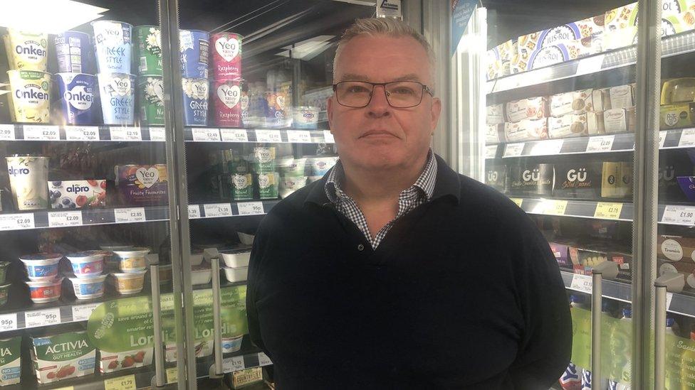 Ben Simons standing in front of fridges in his shop